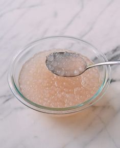 a spoon with some sugar in it on top of a glass bowl filled with water