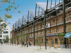 people are walking on the sidewalk in front of an old brick building with solar panels