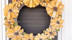 a wreath with yellow flowers hanging on the front door