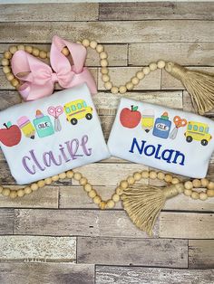 two personalized name blocks with tassels and beads on a wooden floor next to each other