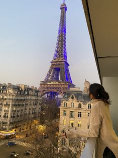 a woman looks out at the eiffel tower from her balcony in paris, france