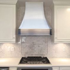 a stove top oven sitting inside of a kitchen next to white cabinets and counter tops