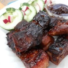 ribs and cucumbers on a white plate with ketchup