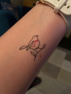 a small tattoo on the arm of a woman's left arm, with a bird holding a knife