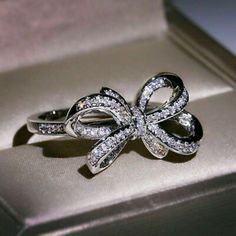 an open box with a ring in it that has a bow on the front and side