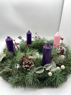 a wreath with purple candles and pine cones