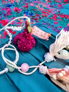 some beads and other items are laying on a blue cloth covered tablecloth with pink flowers