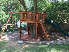 a wooden swing set with a green slide