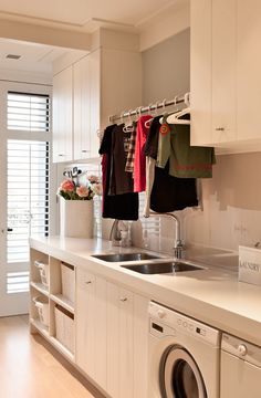 a washer and dryer in a small room with clothes hanging on the rack