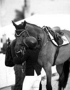 a woman standing next to a brown horse with a saddle on it's back