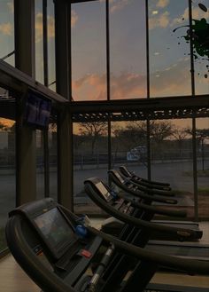 there are many treadmills lined up in front of a window with the sun going down