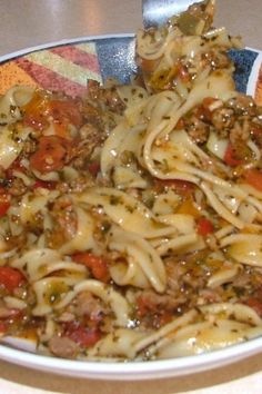 a plate full of pasta with meat and vegetables on it, ready to be eaten