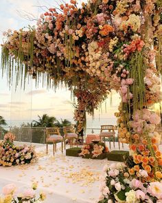 an outdoor wedding setup with flowers and greenery on the ground, overlooking the ocean