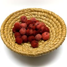 a wicker bowl filled with raspberries on a white surface