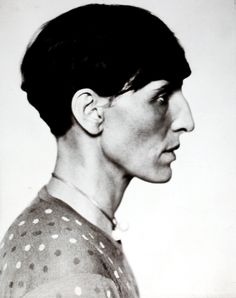 an old black and white photo of a woman with short hair wearing a polka dot shirt