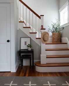 there is a hat on the stairs in this house with wood floors and white walls