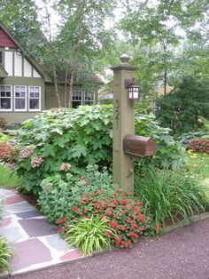 a mailbox surrounded by flowers and greenery in front of a house