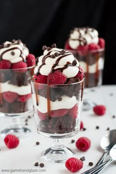 three desserts with chocolate, raspberries and whipped cream in small glass dishes