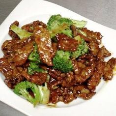 beef and broccoli with sauce on a white plate