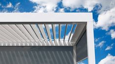 a white awning on the side of a building under a blue sky with clouds