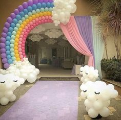 some balloons are in the shape of sheeps and a rainbow arch for an entrance to a party