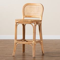 a wicker bar stool sitting on top of a hard wood floor next to a white wall