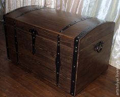 an old trunk is sitting on the floor in front of a white curtain with black handles