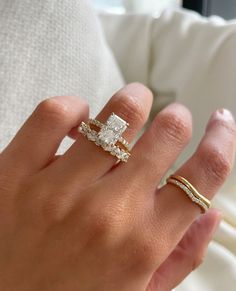 a woman's hand with two rings on her fingers and one ring in the middle