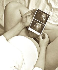 a woman laying in bed with her stomach exposed holding an electronic device to show images