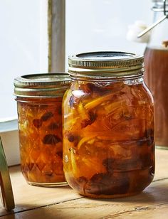 two jars filled with food sitting on top of a wooden table