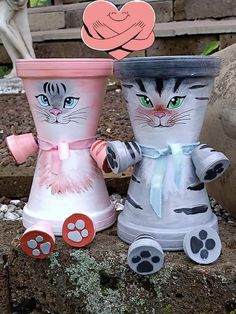 two vases with cats painted on them, one is pink and the other is white