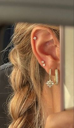 a woman is looking at her cell phone while wearing some earring set in front of her face