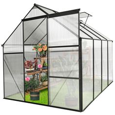 a small greenhouse with plants inside and potted flowers in the corner on the side