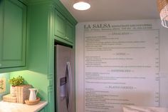 a kitchen with green cabinets and a menu on the wall