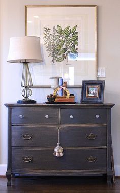 an old dresser with pictures on it and a lamp