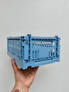 a hand holding up a blue plastic crate