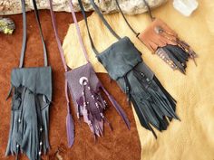 four leather purses are laid out on the ground with different colors and designs hanging from them