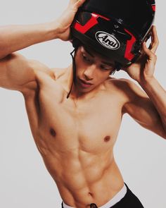 a shirtless man wearing a helmet and no shirt is holding his hands to his head