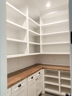 an empty pantry with white cabinets and wood counter tops in a home remodeling project