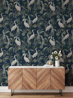 a wallpapered room with birds and flowers on the sideboard in front of it