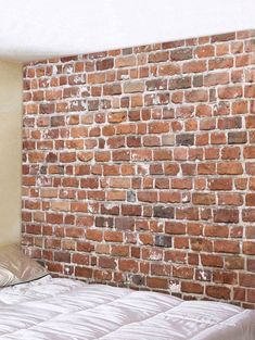 an empty bed in front of a brick wall