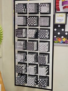 a black and white quilt hanging on the wall next to a table with a vase