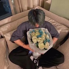 a person sitting on a couch holding a bouquet of flowers