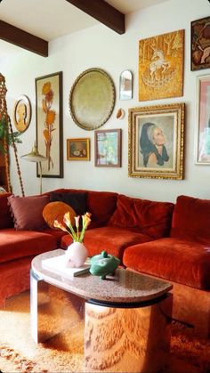 a living room filled with red couches and pictures on the wall above it's coffee table