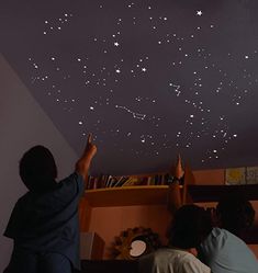 two people are looking up at the stars in the sky on the ceiling above them