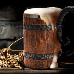 a wooden barrel with white liquid pouring out of it next to some ears of wheat