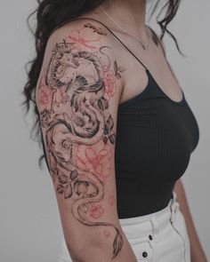 a woman with a dragon and flowers tattoo on her arm is posing for the camera