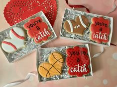 three decorated cookies in boxes with red and white designs on them, one is for you're a catch