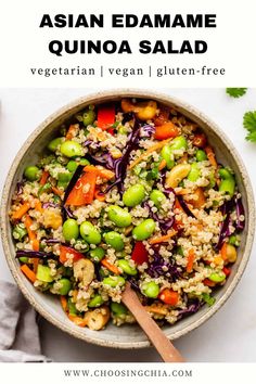 a bowl filled with rice and vegetables on top of a white table next to a wooden spoon