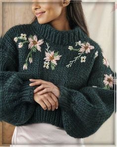 a woman wearing a green sweater with flowers on it